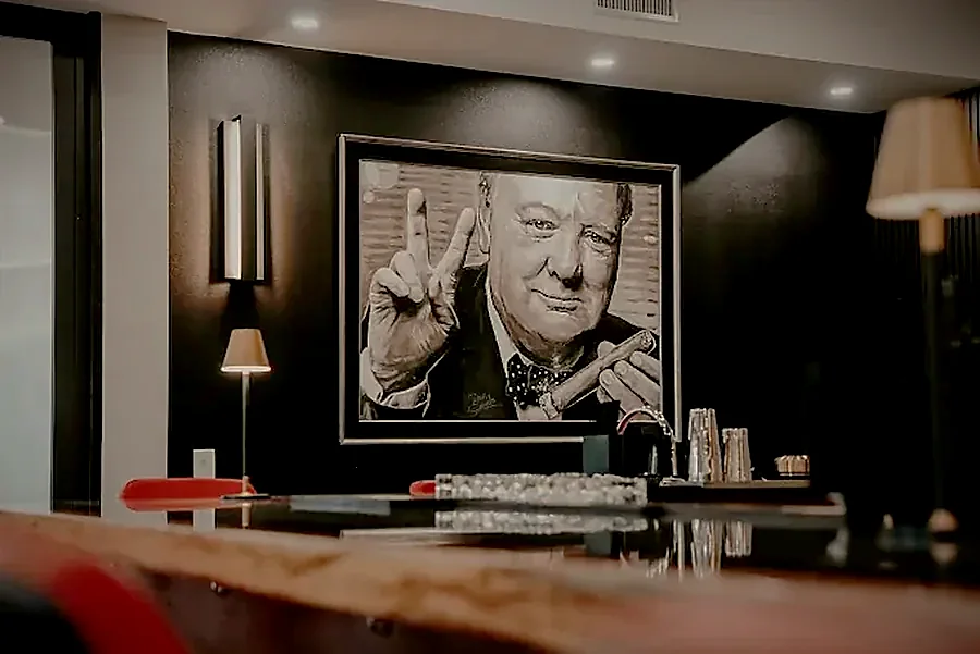 A portrait of Winston Churchill giving the V sign above the bar in low light