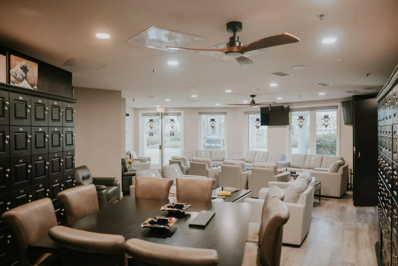 The Guv'nor Room: a board table with leather chairs, walls of humidified lockers and pale leather lounge chairs
