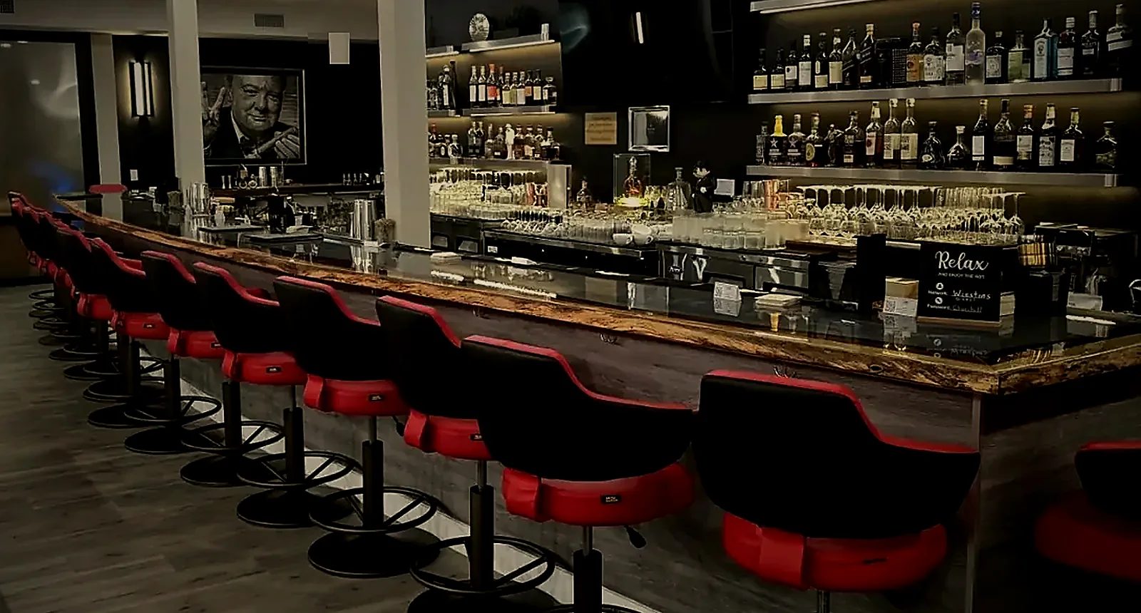 The bar at The Winston's Club, red leather stools along a live-edge counter